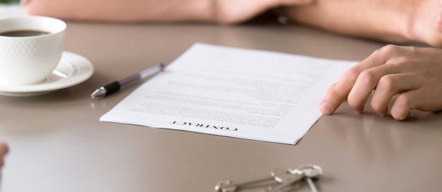 Landlord and tenants reviewing and signing a rental contract with house keys on the table, representing Texas landlord-tenant law agreements.
