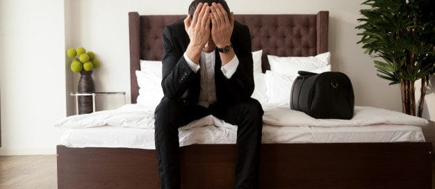 Stressed landlord sitting on a bed with head in hands after preparing an eviction notice letter for a tenant in Texas.