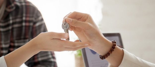 Landlord handing over house keys to tenant, symbolizing lease agreements and legal consequences of breaking a lease in Dallas-Fort Worth, Texas.