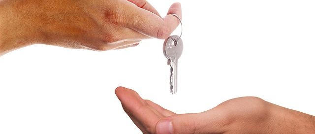 Hand giving a key to another person, symbolizing the relationship and responsibilities between landlords and tenants in Texas.