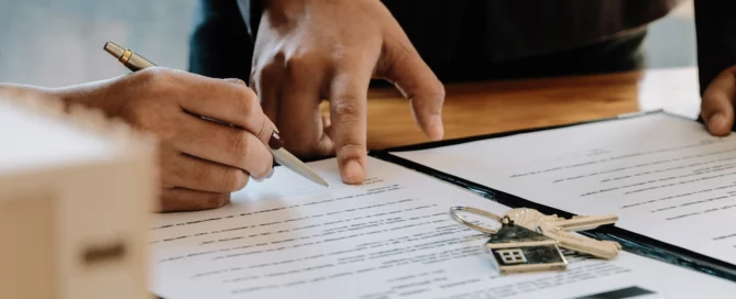 Two hands over a contract with pen and house keychain, illustrating landlord-tenant mediation vs litigation in Dallas-Fort Worth.